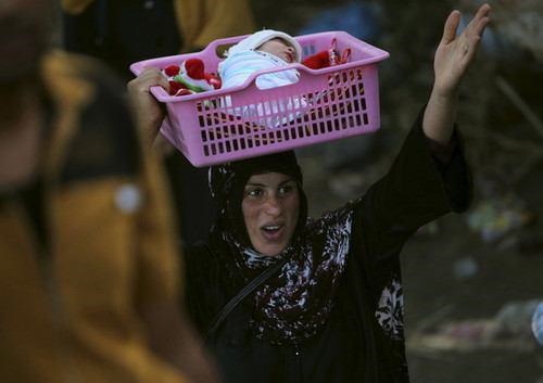 زن آواره عراقی که نوزادش را در سبد حمل می‌کند (عکس)