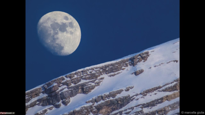 ماه و کوه آنتِلائو – رنگ‌های سفیدِ روی کوه ماده معدنی «دولومیت» هستند که آن را شبیه یک کوه برفی کرده است. 
