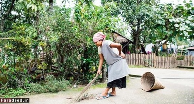 زنی مشغول جارو کردن زباله‌ها در روستای مالینونگ 