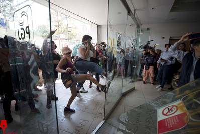  معترضان خشمگین در حال شکستن در شیشه‌ای ورودی ساختمان دادستانی کل مکزیک در شهر 