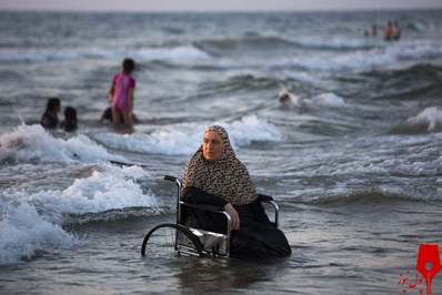 زنی از شهر کرانه باختری در  جشنواره عید قربان در دریای مدیترانه نشسته‌است/ فلسطین