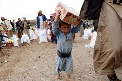 کودکی جیره‌های غذایی را که توسط گروه خیریه Mona تامین می‌شود حمل می‌کند/ صنعا، یمن